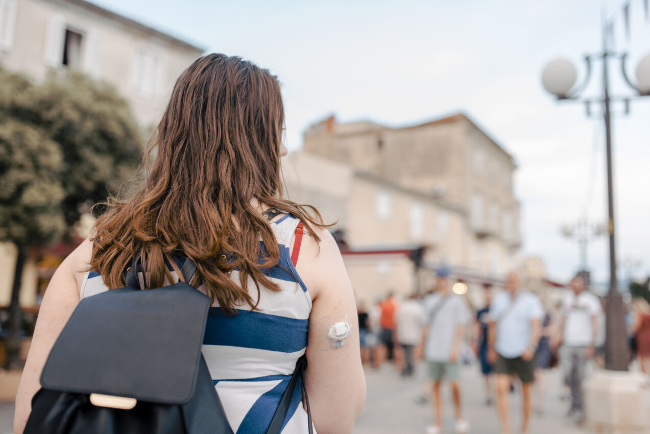 Young woman exploring the city wearing a continuous glucose monitor and a backpack