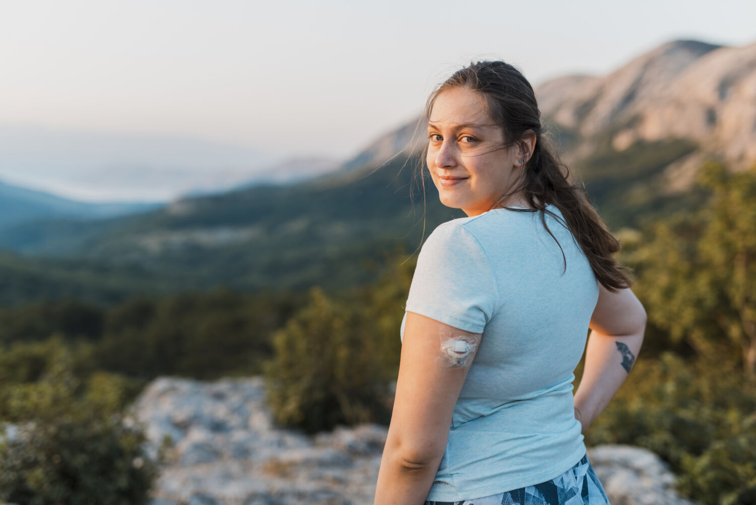 Woman with diabetes standing on top of the hill and looking at camera